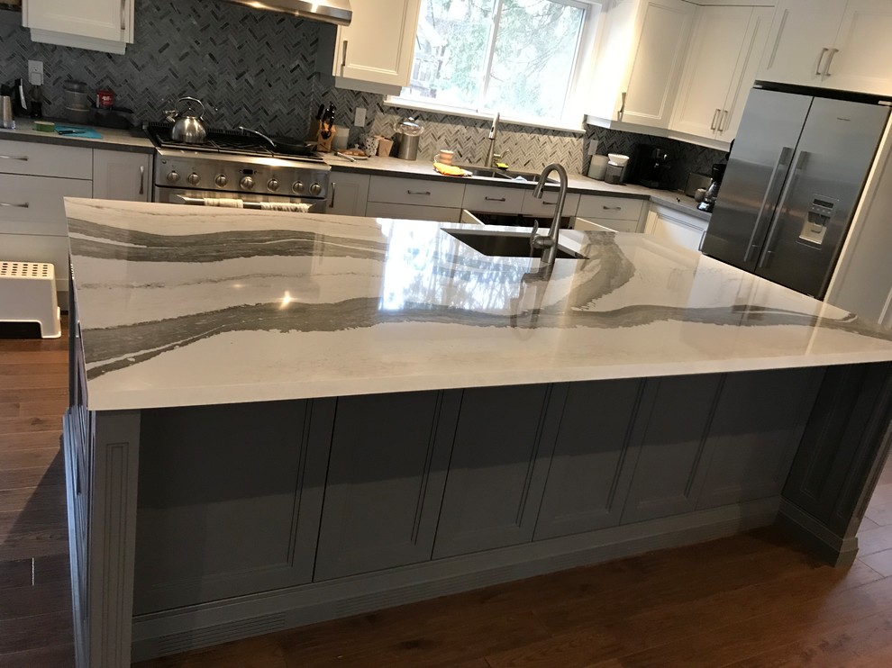 Large transitional l-shaped dark wood floor and brown floor eat-in kitchen photo in Toronto with an undermount sink, recessed-panel cabinets, gray cabinets, solid surface countertops, gray backsplash, mosaic tile backsplash, stainless steel appliances, an island and multicolored countertops