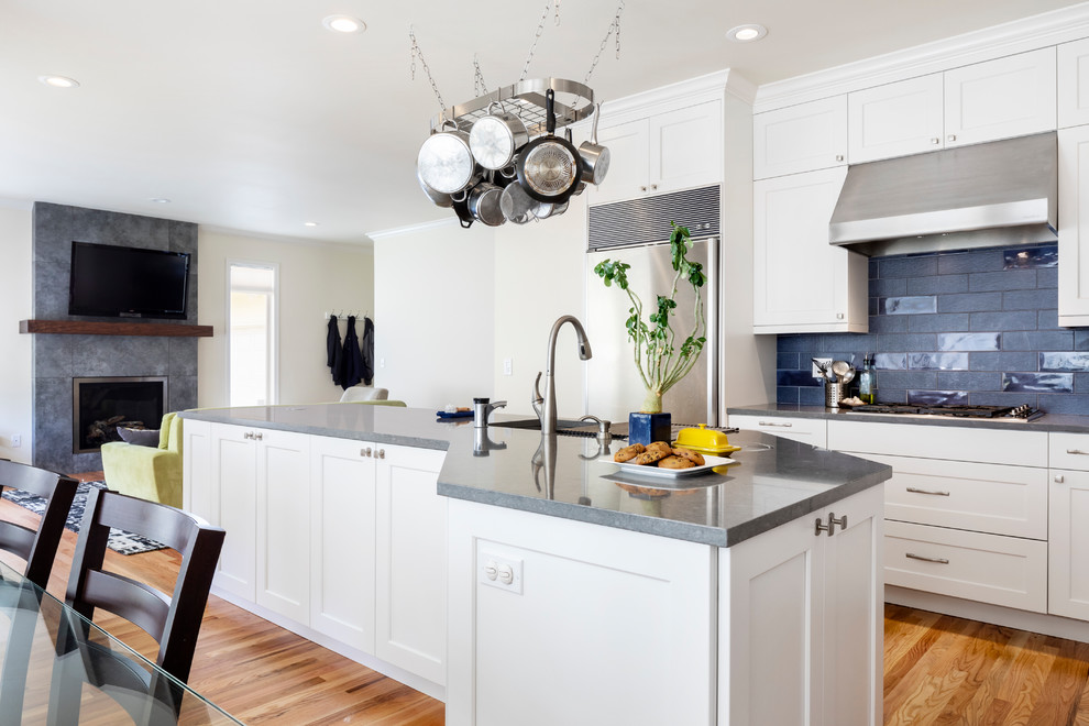 This is an example of a mid-sized contemporary l-shaped eat-in kitchen in Seattle with an undermount sink, shaker cabinets, white cabinets, quartz benchtops, blue splashback, ceramic splashback, stainless steel appliances, medium hardwood floors, with island and grey benchtop.