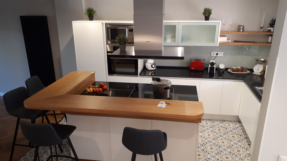 Photo of a mid-sized contemporary l-shaped open plan kitchen in Madrid with an undermount sink, white cabinets, granite benchtops, grey splashback, window splashback, stainless steel appliances, ceramic floors, with island, turquoise floor and black benchtop.