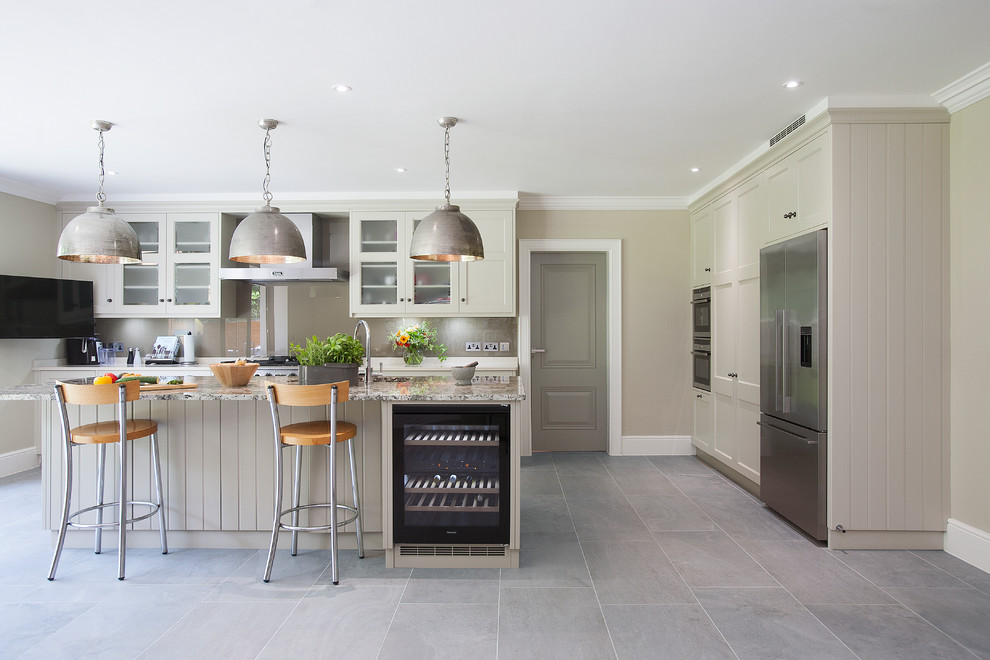 Design ideas for a transitional kitchen in Surrey with recessed-panel cabinets, grey cabinets, grey splashback, glass sheet splashback, stainless steel appliances and with island.