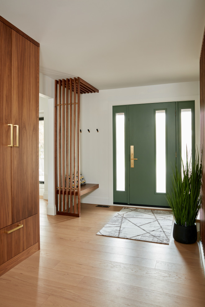 Exempel på en mellanstor 60 tals foajé, med vita väggar, ljust trägolv, en enkeldörr, en grön dörr och brunt golv