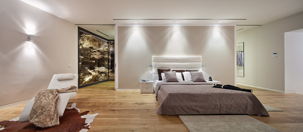 Photo of a large modern master bedroom in Palma de Mallorca with beige walls, medium hardwood floors, no fireplace and brown floor.