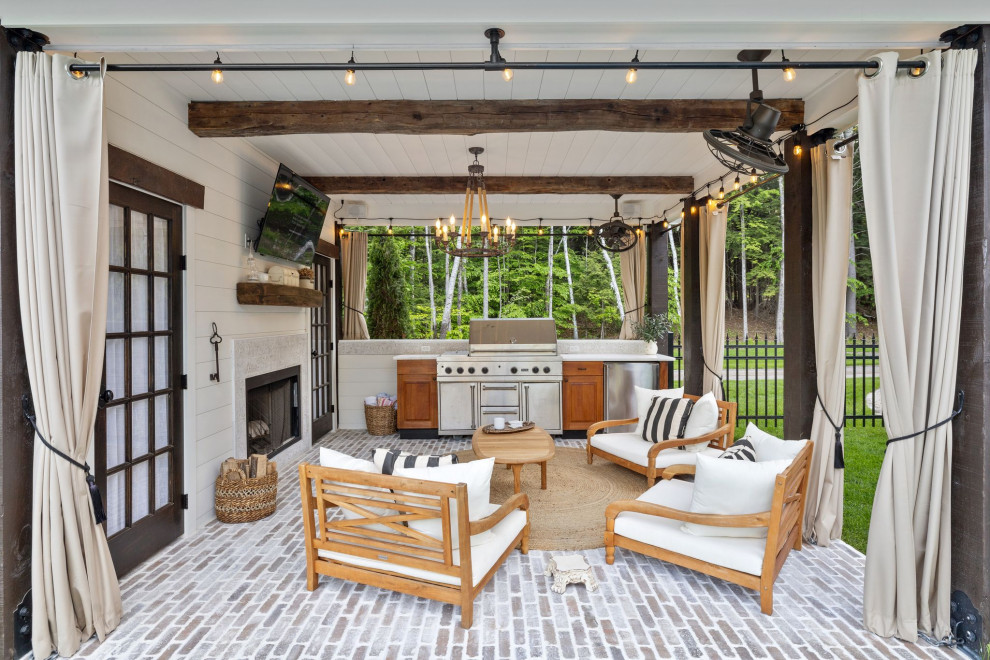 На фото: двор на заднем дворе в стиле кантри с мощением клинкерной брусчаткой, навесом и зоной барбекю