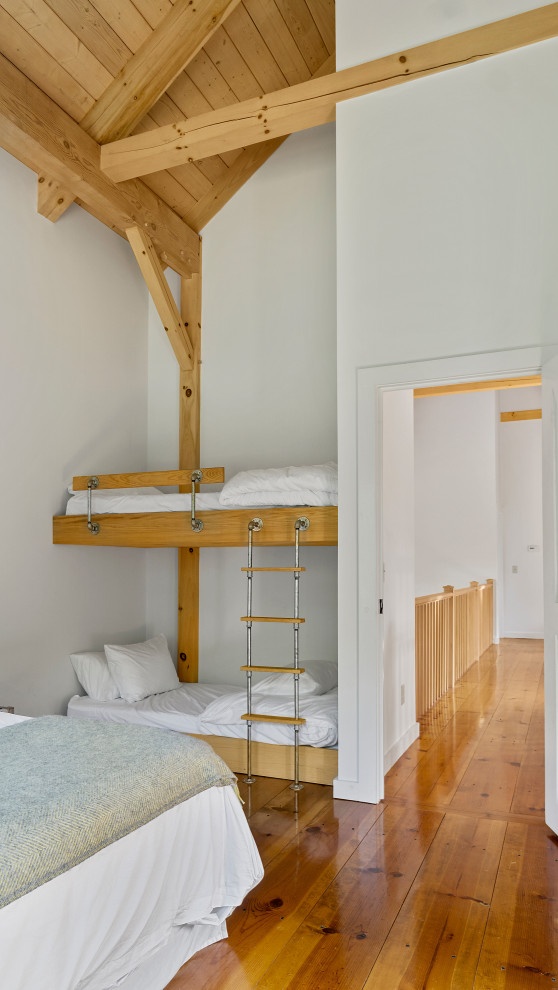 Inspiration for a large country guest bedroom in New York with white walls, medium hardwood floors and exposed beam.