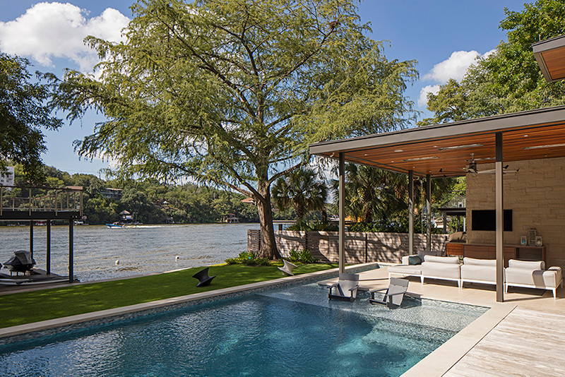 Photo of a mid-sized contemporary backyard custom-shaped lap pool in Austin with a hot tub and decking.