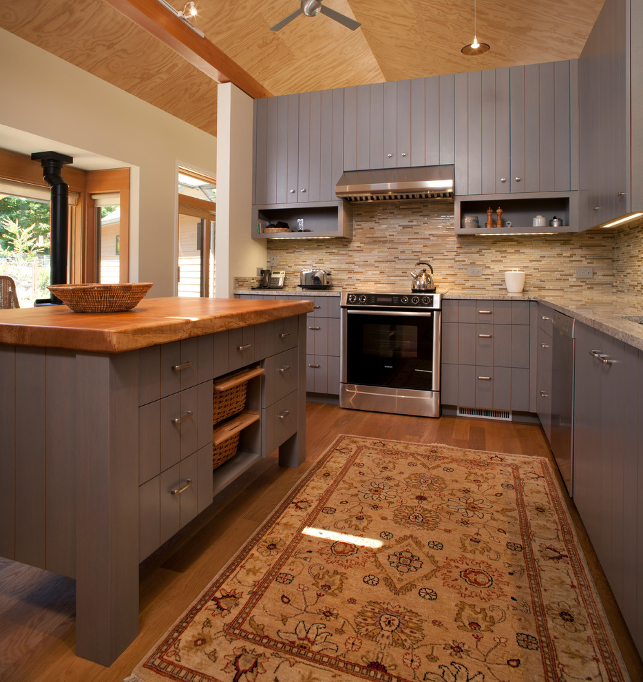 Mid-sized country u-shaped eat-in kitchen in Seattle with an undermount sink, louvered cabinets, grey cabinets, granite benchtops, beige splashback, matchstick tile splashback, stainless steel appliances, medium hardwood floors and with island.