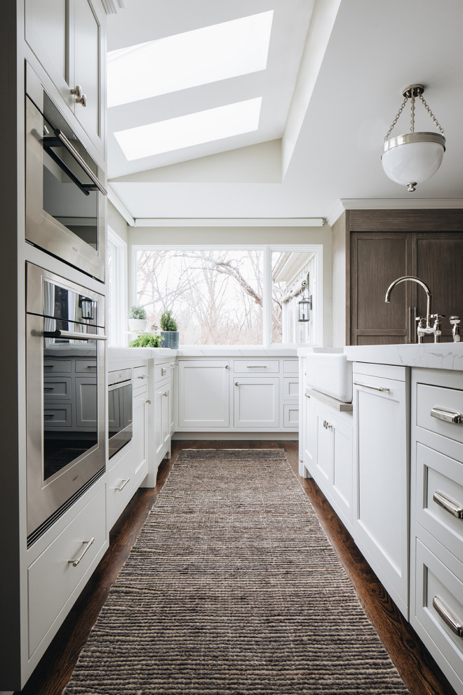 Inspiration for a mid-sized transitional dark wood floor and brown floor eat-in kitchen remodel in Chicago with a farmhouse sink, beaded inset cabinets, white cabinets, quartz countertops, paneled appliances, an island and white countertops