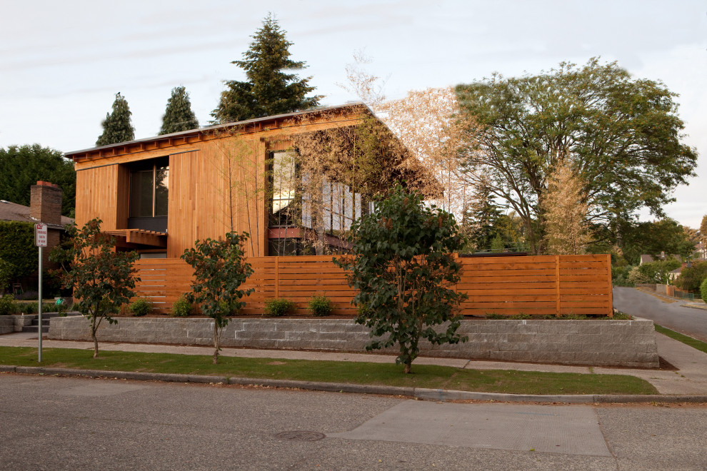 Ejemplo de fachada de casa naranja moderna de tamaño medio de dos plantas con revestimiento de madera y tejado plano