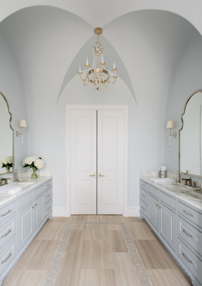 Large master bathroom in Dallas with beaded inset cabinets, blue cabinets, a claw-foot tub, a corner shower, beige tile, limestone, blue walls, limestone floors, marble benchtops, beige floor, a hinged shower door, white benchtops, a shower seat, a built-in vanity, vaulted, an undermount sink and a double vanity.