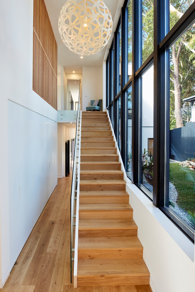 Photo of a contemporary wood straight staircase in Sydney with wood risers and glass railing.