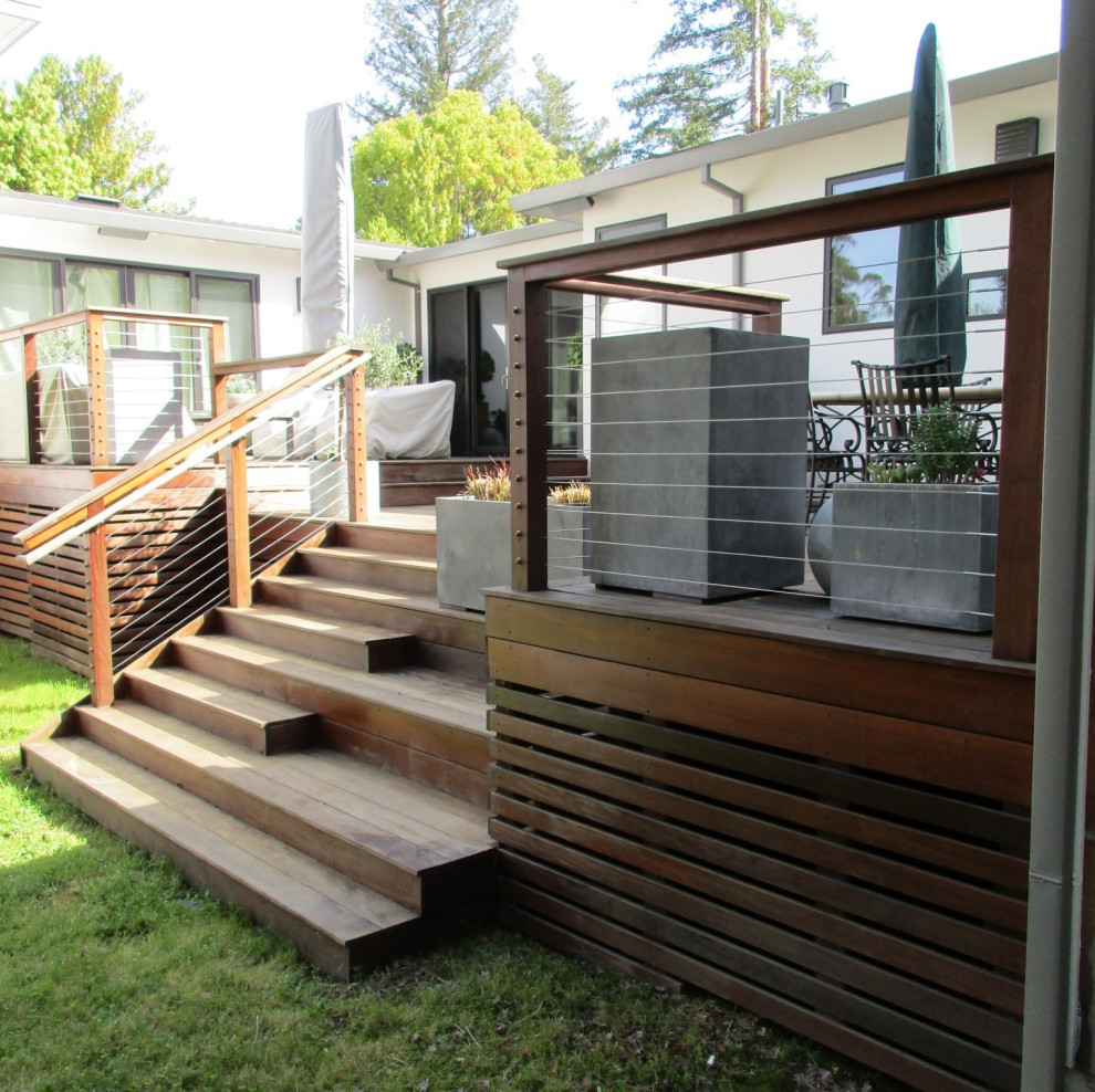 Diseño de terraza retro de tamaño medio en patio trasero con barandilla de cable