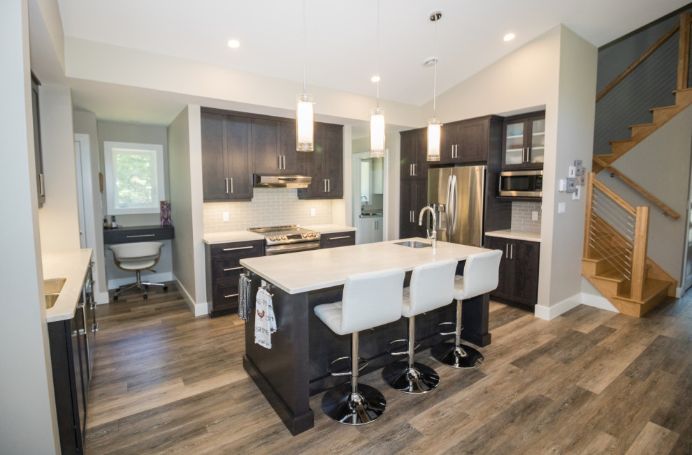 Kitchen - mid-sized u-shaped vinyl floor and brown floor kitchen idea with an undermount sink, recessed-panel cabinets, dark wood cabinets, quartzite countertops, gray backsplash, subway tile backsplash, stainless steel appliances, an island and white countertops