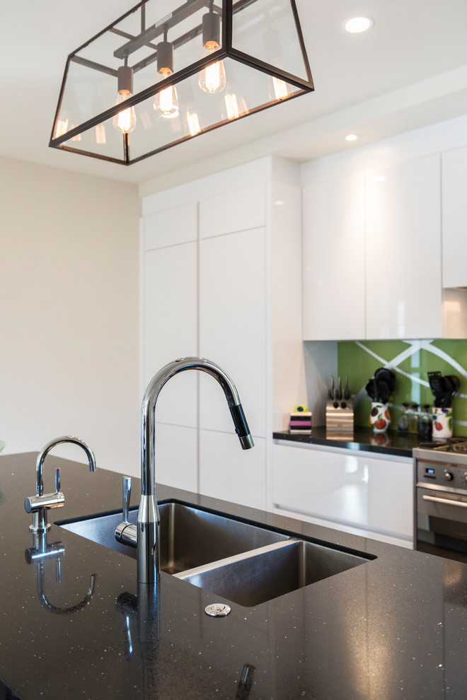 Photo of a Mid-sized contemporary Galley kitchen pantry in Christchurch With an Undermount Sink, Flat-panel Cabinets, Yellow Cabinets, Quartz Benchtops, Green Splashback, Glass Sheet Splashback, Stainless Steel Appliances, Light Hardwood Floors, with Island and Brown Floor.