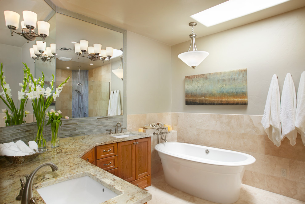 Inspiration for a mid-sized transitional master bathroom in Phoenix with shaker cabinets, medium wood cabinets, a freestanding tub, gray tile, matchstick tile, beige walls, limestone floors, an undermount sink, granite benchtops and beige floor.