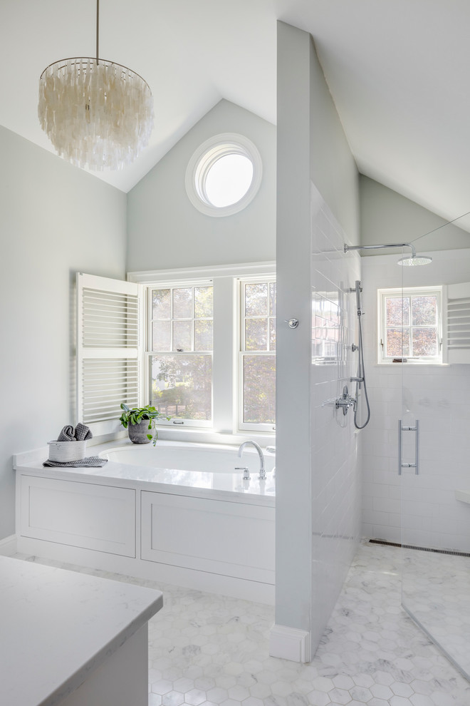 Inspiration for a mid-sized transitional master bathroom in Boston with recessed-panel cabinets, white cabinets, a drop-in tub, an alcove shower, a one-piece toilet, white tile, grey walls, ceramic floors, a console sink, marble benchtops, white floor and a hinged shower door.