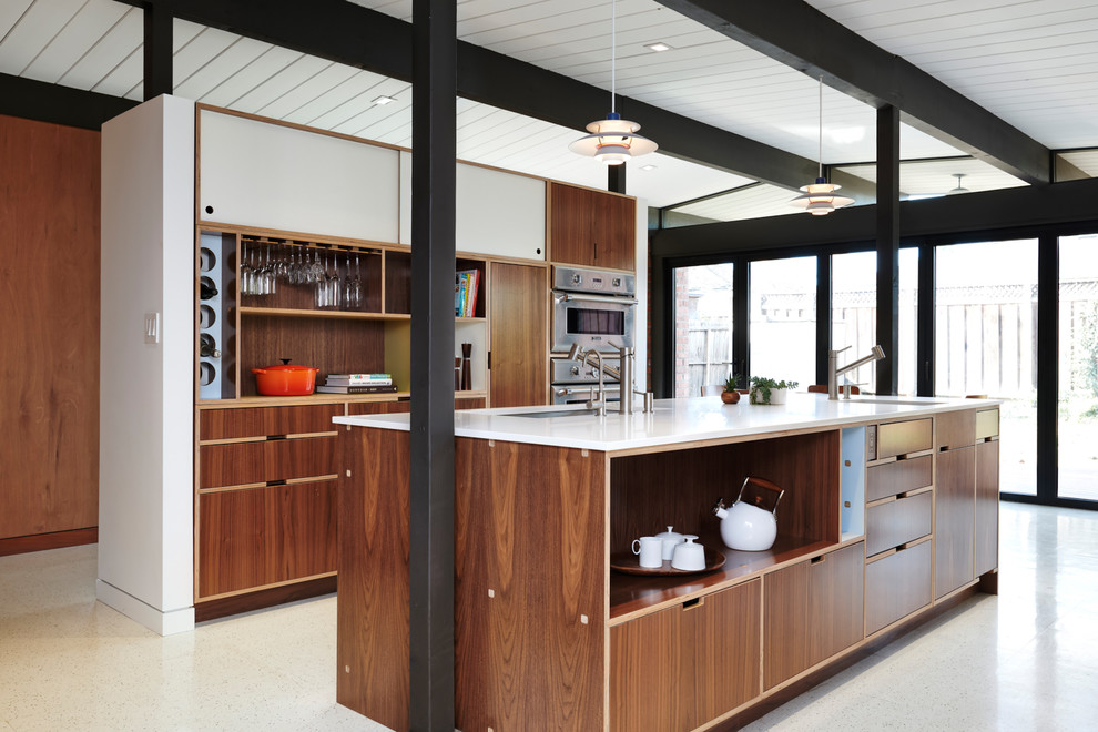 This is an example of a midcentury galley kitchen in San Francisco with an undermount sink, flat-panel cabinets, dark wood cabinets, stainless steel appliances, with island, white floor and white benchtop.