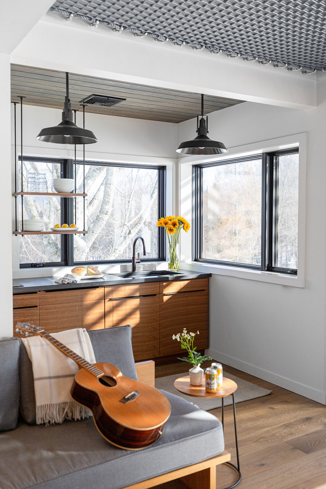 Photo of a contemporary single-wall kitchen in Burlington with an undermount sink, flat-panel cabinets, medium wood cabinets, zinc benchtops, medium hardwood floors, grey benchtop and vaulted.