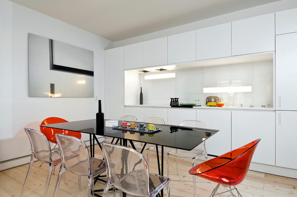 This is an example of a mid-sized scandinavian single-wall eat-in kitchen in Paris with flat-panel cabinets, white cabinets, white splashback and glass sheet splashback.