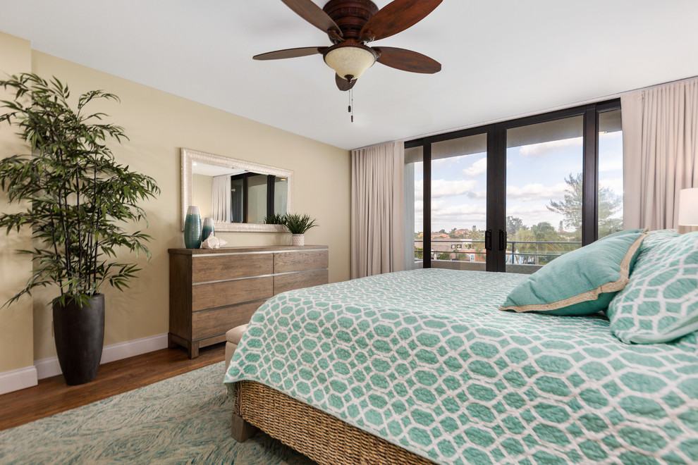 Mid-sized beach style master bedroom in Tampa with yellow walls, bamboo floors, no fireplace and brown floor.