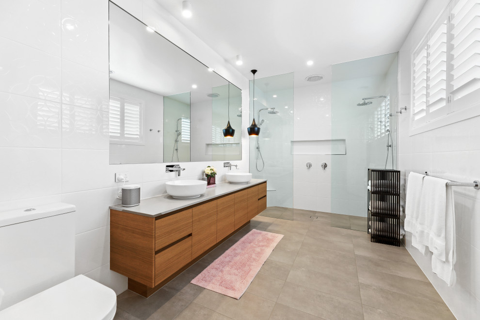 Inspiration for a contemporary master beige floor and double-sink bathroom remodel in Other with flat-panel cabinets, medium tone wood cabinets, a two-piece toilet, white walls, a vessel sink, quartz countertops, gray countertops and a floating vanity