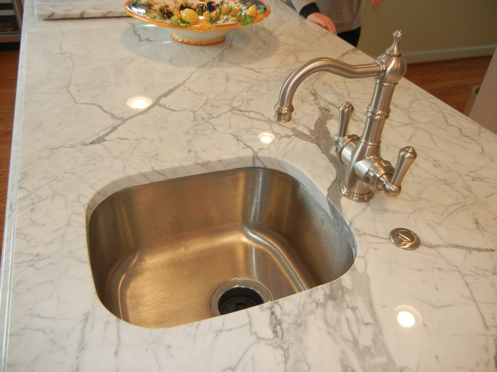 Large transitional u-shaped medium tone wood floor and brown floor open concept kitchen photo with an undermount sink, shaker cabinets, white cabinets, stainless steel appliances, an island, white backsplash, subway tile backsplash, marble countertops and white countertops
