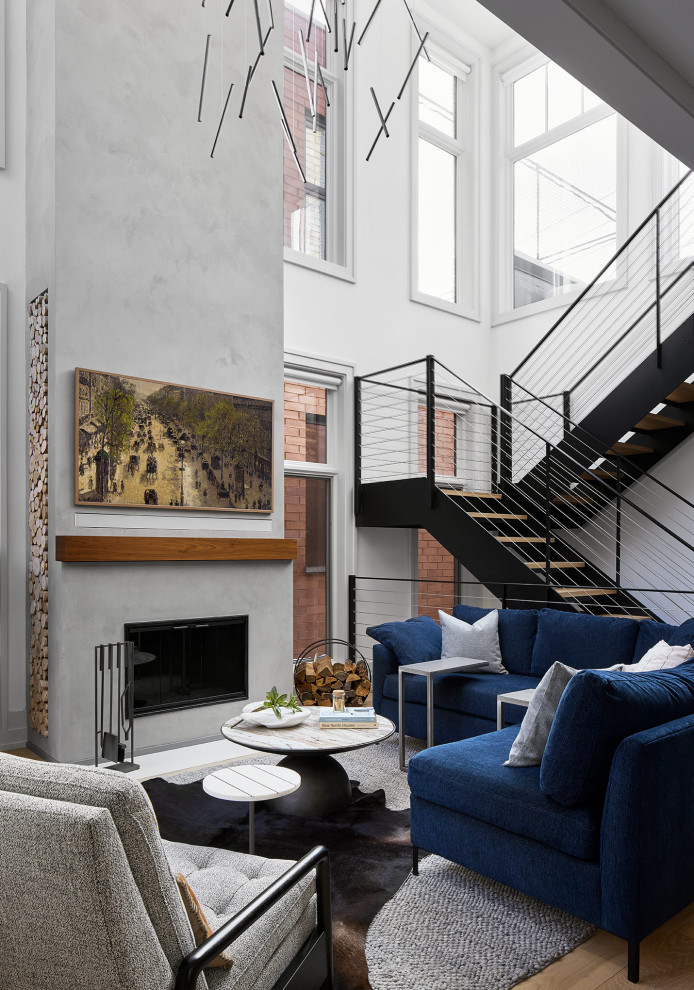 Contemporary open concept living room in Chicago with white walls, light hardwood floors, a standard fireplace, a concrete fireplace surround, a concealed tv and vaulted.