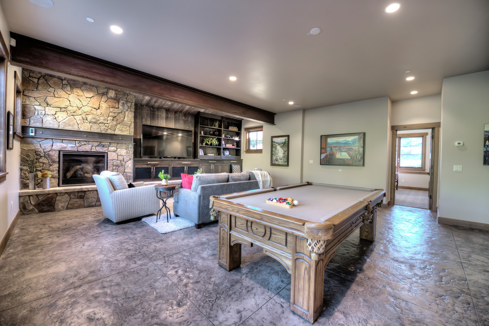 Inspiration for a large transitional open concept family room with a game room, concrete floors, a hanging fireplace, a stone fireplace surround and a freestanding tv.