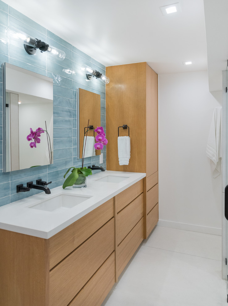 Mid-sized beach style master bathroom with flat-panel cabinets, light wood cabinets, a curbless shower, a one-piece toilet, white tile, porcelain tile, white walls, porcelain floors, an undermount sink, engineered quartz benchtops, white floor, a hinged shower door and white benchtops.