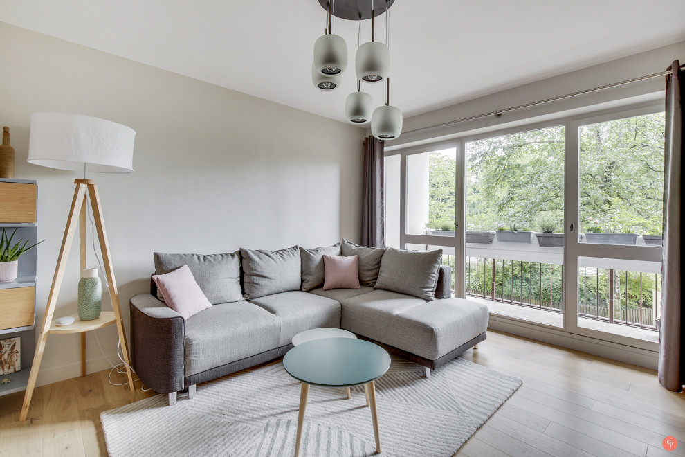 Mid-sized danish enclosed light wood floor and brown floor family room photo in Paris with beige walls and a wall-mounted tv