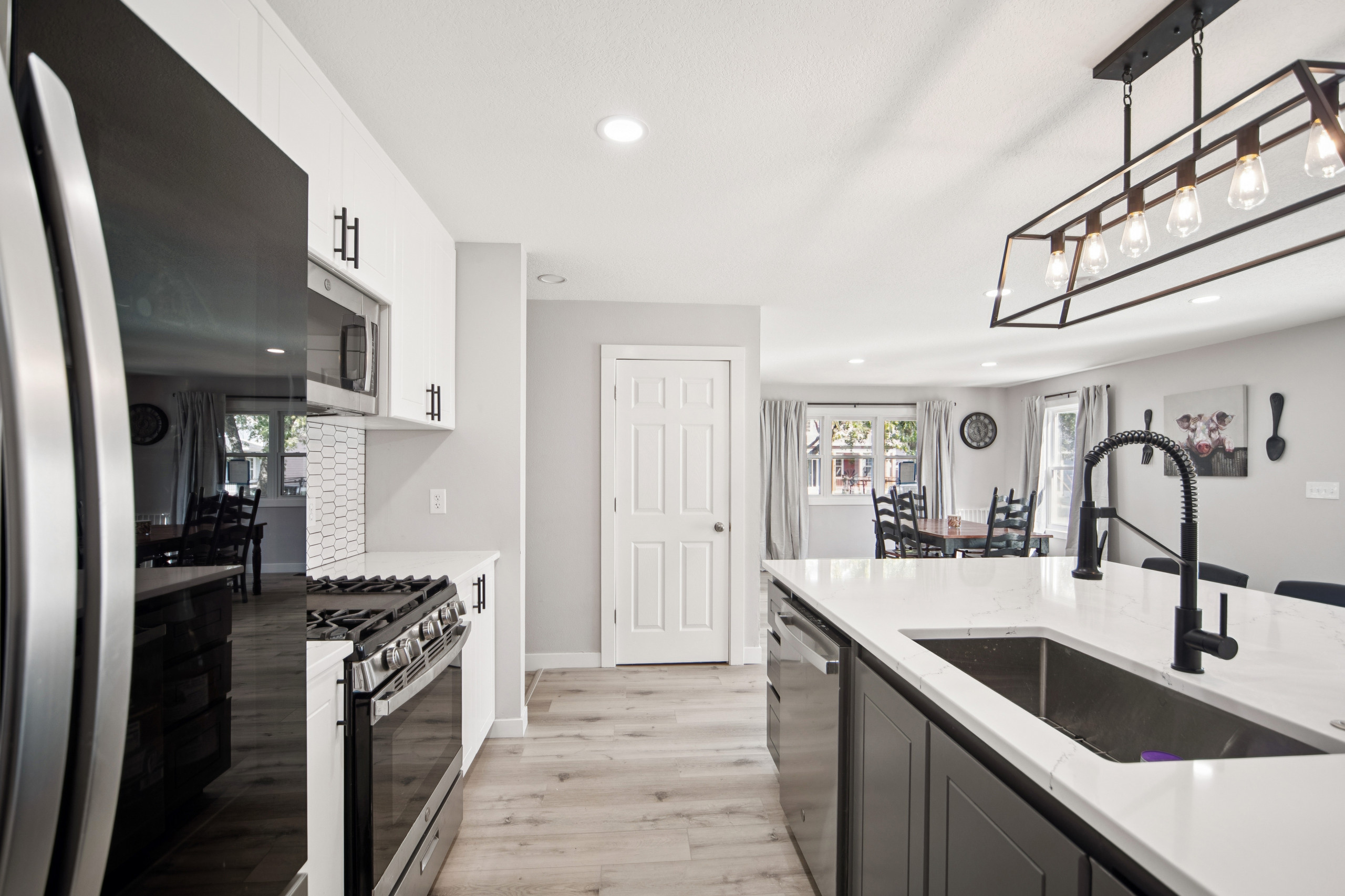 Vinyl floor kitchen photo in Other with white cabinets, ceramic backsplash and an island