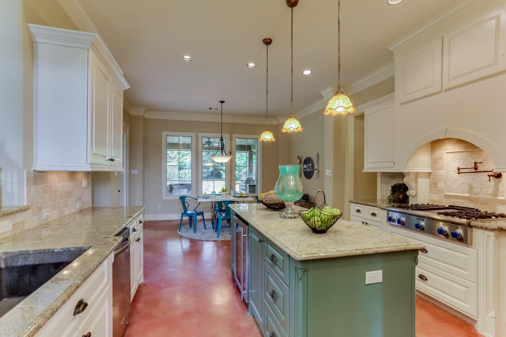 Mid-sized transitional u-shaped concrete floor and brown floor enclosed kitchen photo in Houston with an undermount sink, raised-panel cabinets, white cabinets, granite countertops, beige backsplash, stone tile backsplash, stainless steel appliances and an island