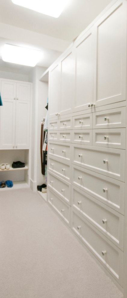 Design ideas for a mid-sized traditional gender-neutral walk-in wardrobe in Minneapolis with recessed-panel cabinets, white cabinets and carpet.