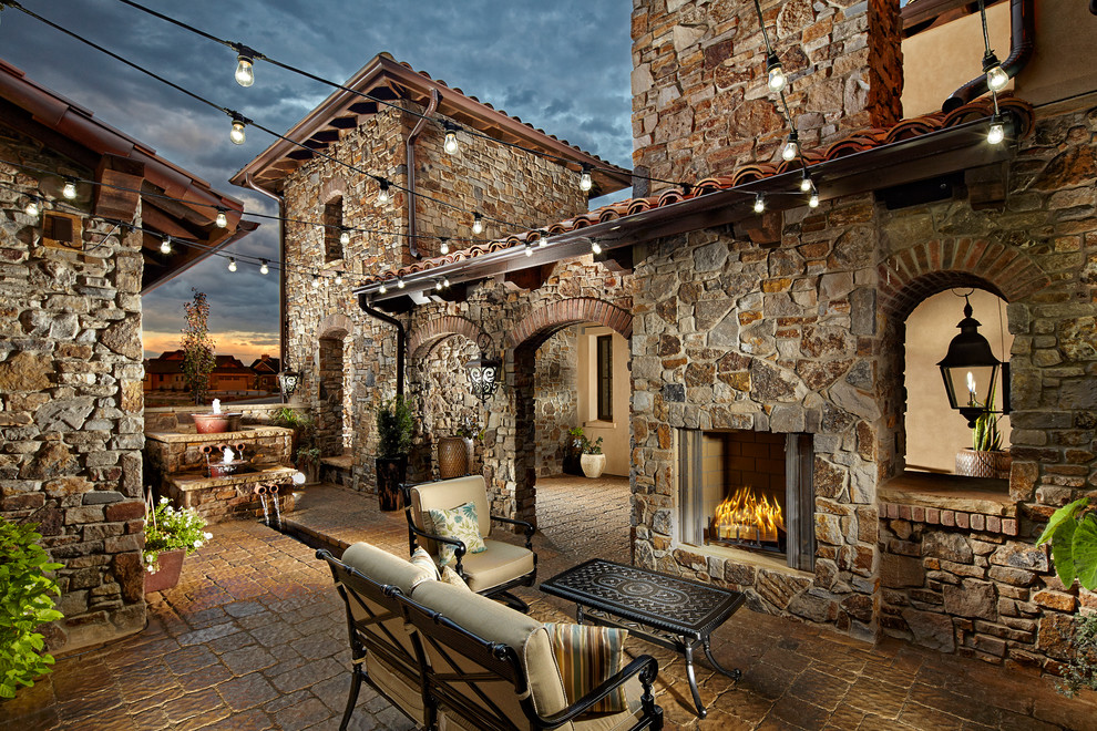 Inspiration for a mediterranean courtyard patio in Denver with natural stone pavers, no cover and with fireplace.