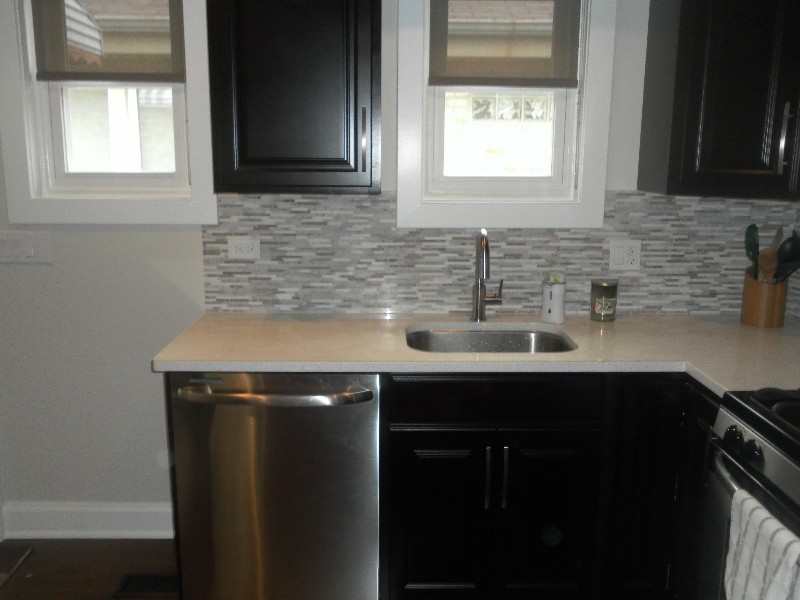 Kitchen - transitional kitchen idea in Chicago with an undermount sink, dark wood cabinets, gray backsplash, matchstick tile backsplash and stainless steel appliances