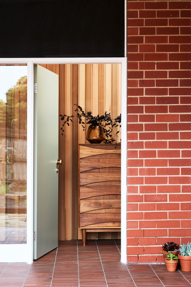 Inspiration for a mid-sized midcentury front door in Sydney with red walls, brick floors, a single front door, a green front door, red floor and brick walls.