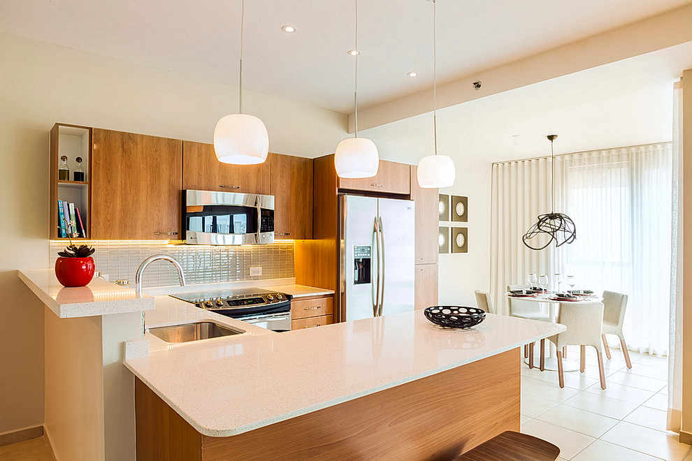 This is an example of a small contemporary u-shaped eat-in kitchen in Other with an undermount sink, flat-panel cabinets, medium wood cabinets, stainless steel appliances, a peninsula, quartz benchtops, grey splashback, glass tile splashback and porcelain floors.