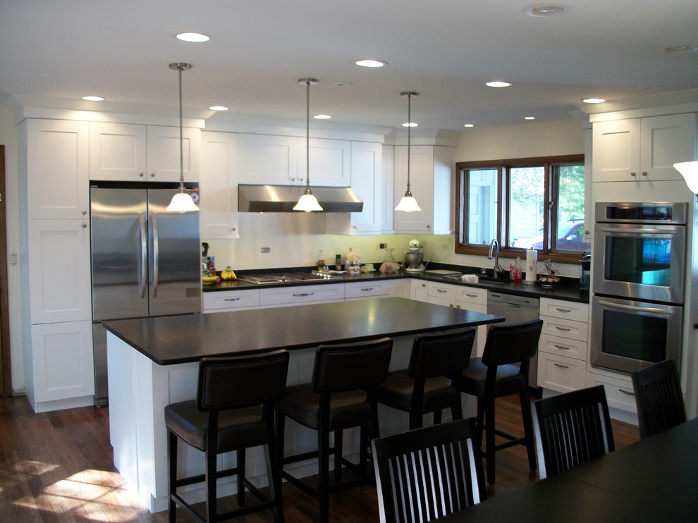 Transitional medium tone wood floor kitchen photo in Chicago with a drop-in sink, white backsplash, stainless steel appliances and an island