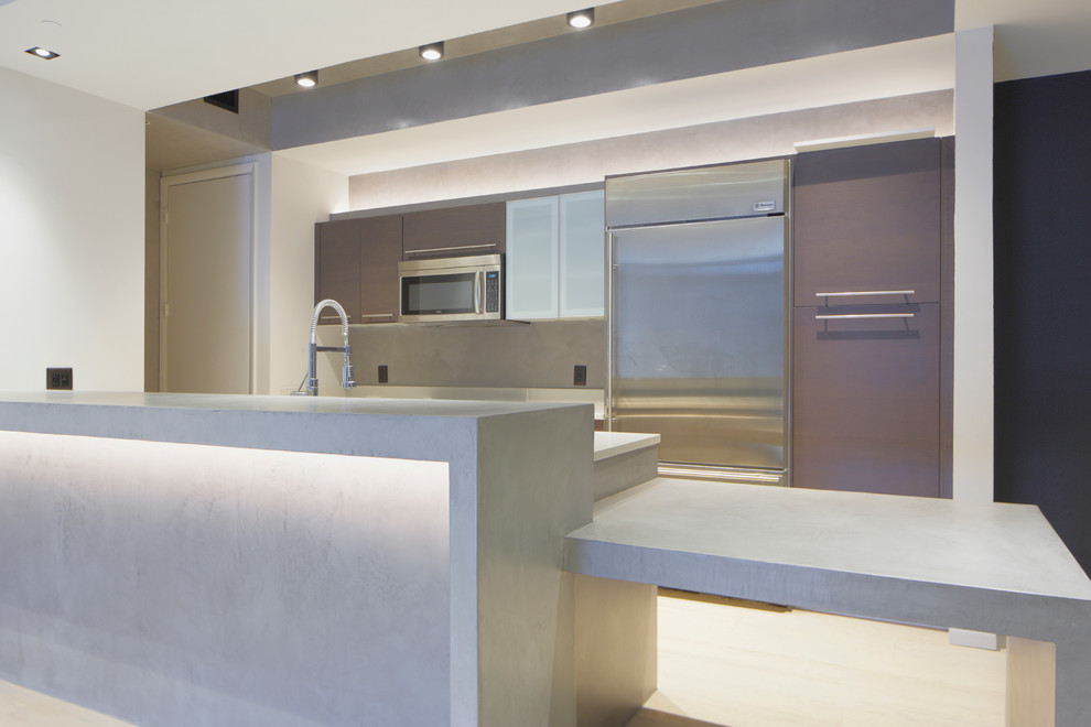 This is an example of a mid-sized contemporary galley kitchen in Miami with flat-panel cabinets, brown cabinets, concrete benchtops, grey splashback, stainless steel appliances, light hardwood floors and a peninsula.