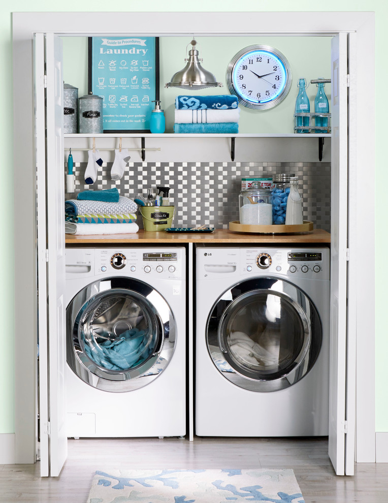 Inspiration for a small transitional single-wall laundry cupboard in Charlotte with wood benchtops, light hardwood floors, a side-by-side washer and dryer, beige benchtop and green walls.