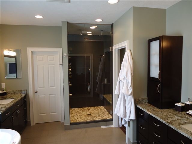 Photo of a modern master bathroom in Indianapolis with an undermount sink, flat-panel cabinets, dark wood cabinets, granite benchtops, a freestanding tub, an alcove shower, multi-coloured tile, mosaic tile, beige walls and ceramic floors.