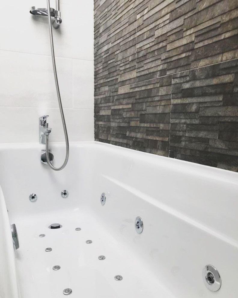 Inspiration for a mid-sized modern master bathroom in London with flat-panel cabinets, white cabinets, a hot tub, a shower/bathtub combo, a two-piece toilet, black tile, porcelain tile, white walls, porcelain floors, a drop-in sink, black floor, an open shower, a single vanity, a floating vanity and recessed.