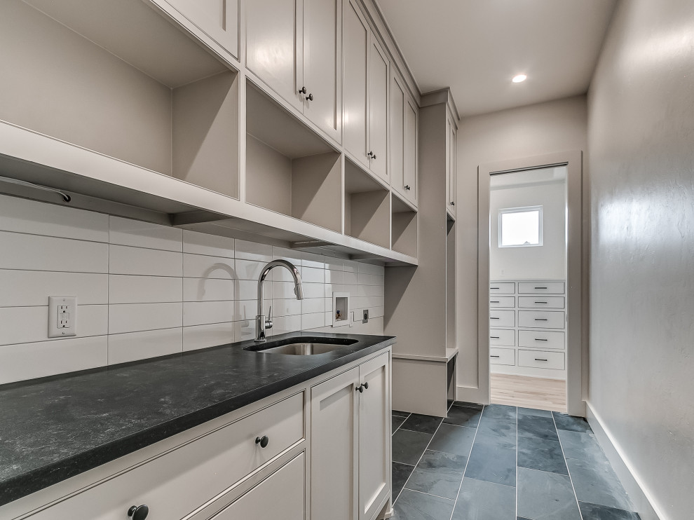 Inspiration for a transitional laundry room in Oklahoma City with an undermount sink, beaded inset cabinets, granite benchtops, white splashback, ceramic splashback, slate floors, a side-by-side washer and dryer and black benchtop.