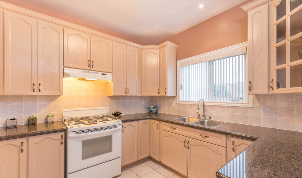 Example of a mid-sized transitional u-shaped ceramic tile eat-in kitchen design in Toronto with a double-bowl sink, recessed-panel cabinets, light wood cabinets, laminate countertops, beige backsplash, ceramic backsplash, white appliances and no island