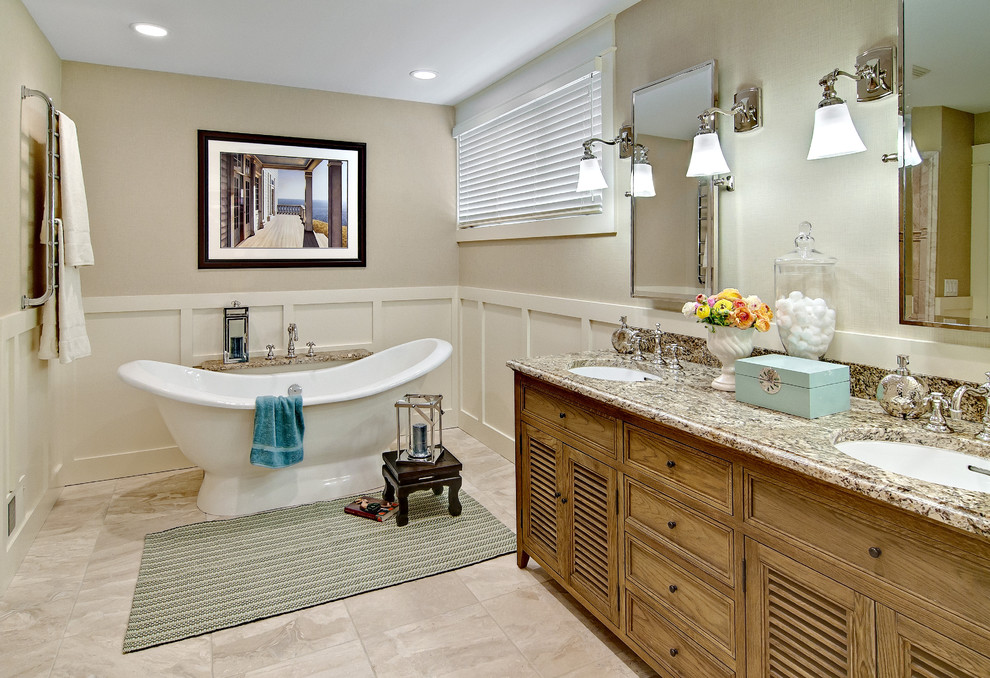 This is an example of a mid-sized beach style master bathroom in Minneapolis with louvered cabinets, distressed cabinets, a freestanding tub, beige walls, travertine floors, an undermount sink and granite benchtops.