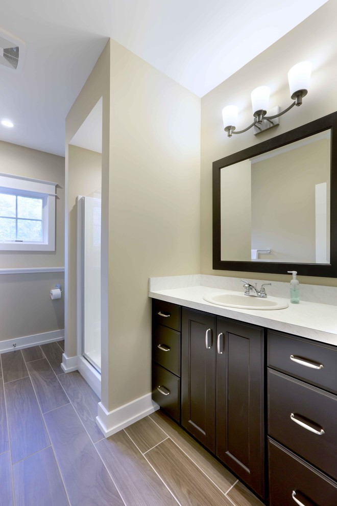 Design ideas for an arts and crafts master bathroom in Grand Rapids with recessed-panel cabinets, dark wood cabinets, an alcove shower, beige walls, dark hardwood floors, a drop-in sink, engineered quartz benchtops, brown floor and a hinged shower door.