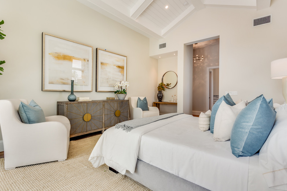 Diseño de dormitorio principal y abovedado costero con paredes beige y suelo de madera en tonos medios