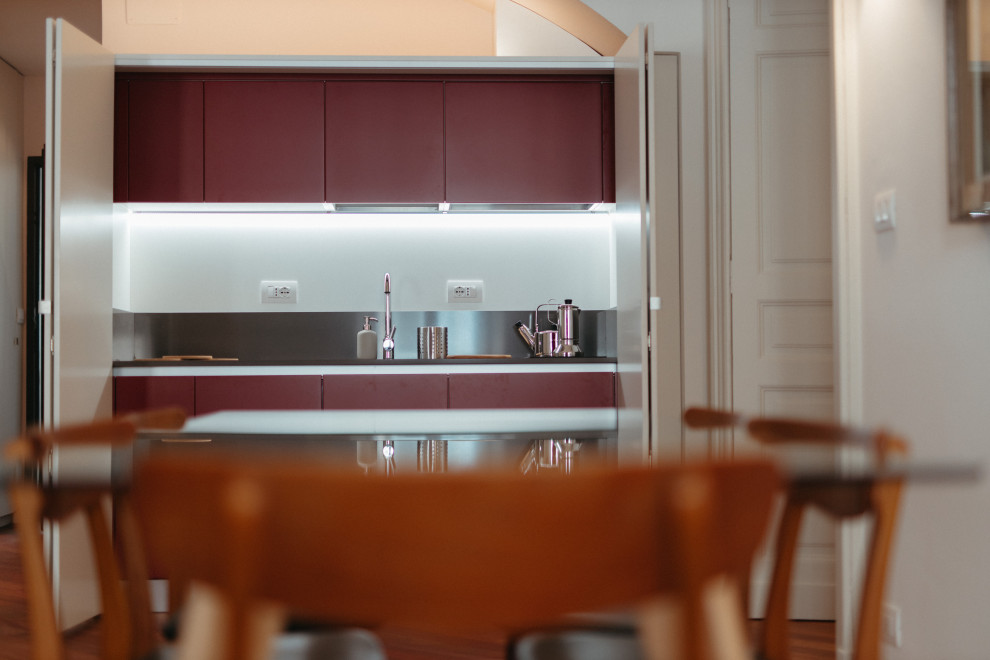 Imagen de cocina lineal contemporánea pequeña abierta sin isla con armarios con rebordes decorativos, puertas de armario rojas, encimera de cuarzo compacto y encimeras negras