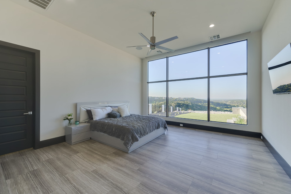 Inspiration for a large modern guest bedroom in Austin with white walls, porcelain floors and brown floor.