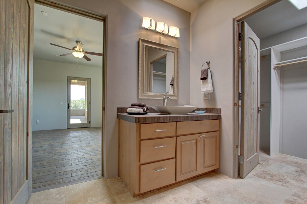 This is an example of a large traditional ensuite bathroom in Albuquerque with raised-panel cabinets, light wood cabinets, grey walls, porcelain flooring, a vessel sink, tiled worktops, beige floors, grey worktops, feature lighting, a single sink and a built in vanity unit.