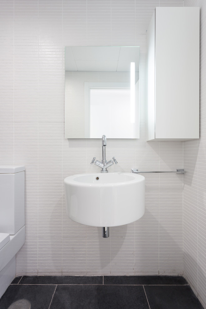 Small contemporary powder room in Other with flat-panel cabinets, white cabinets, white walls and a wall-mount sink.